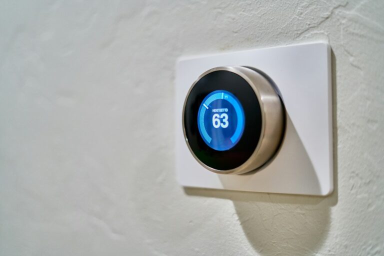 A round wall-mounted thermostat with a blue temperature display.