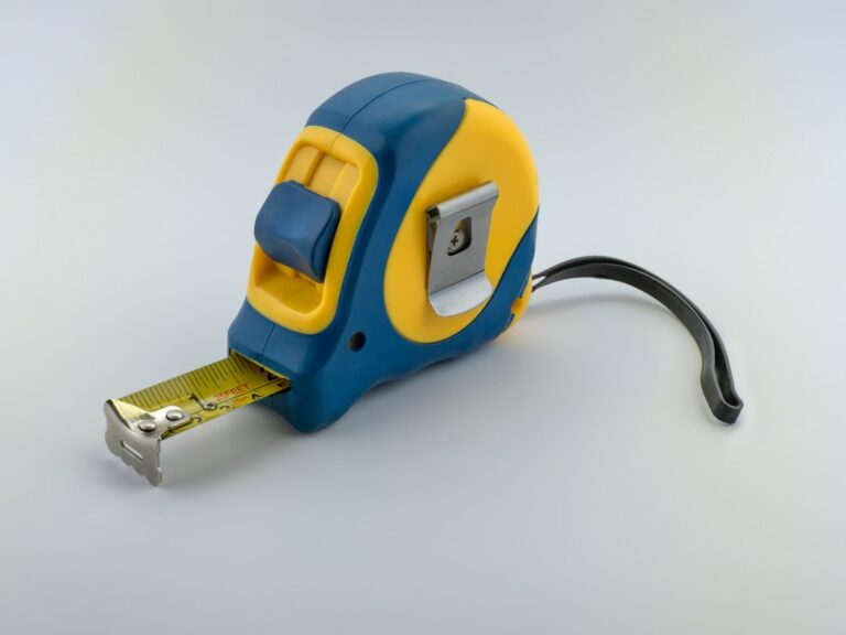 Blue and yellow tape measure on a light surface.