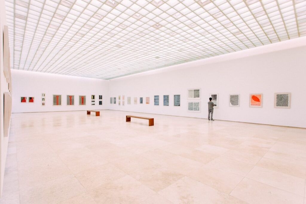 A visitor looking at artwork in a spacious, brightly lit gallery.
