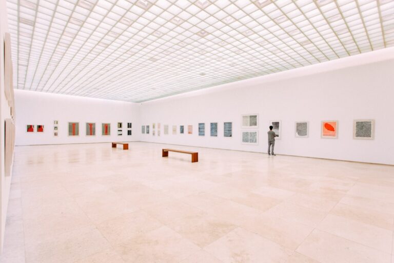 A visitor looking at artwork in a spacious, brightly lit gallery.