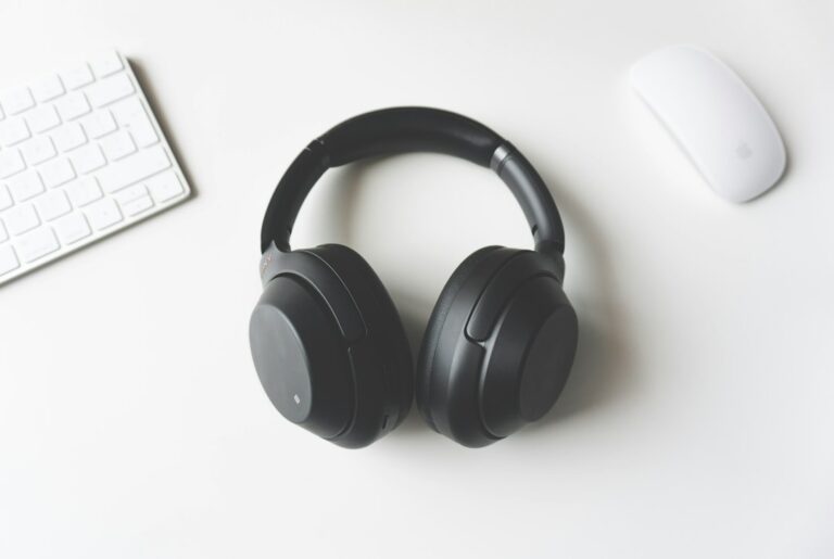 Black headphones between a white keyboard and mouse.