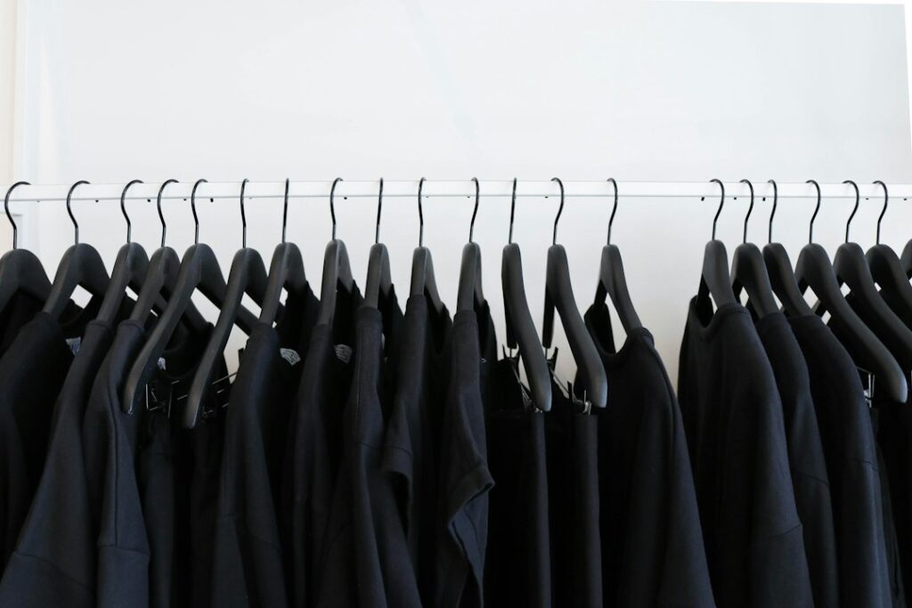 Dark garments arranged on black hangers along a rail