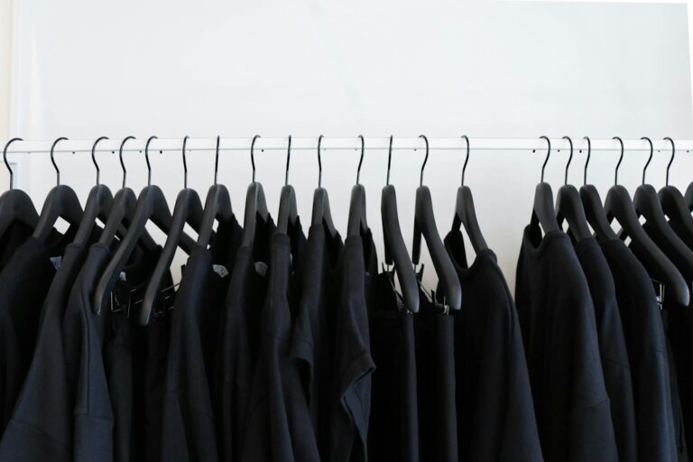 Dark garments arranged on black hangers along a rail