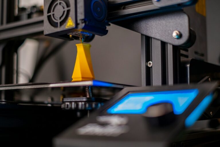 Desktop 3D printer producing a small yellow object