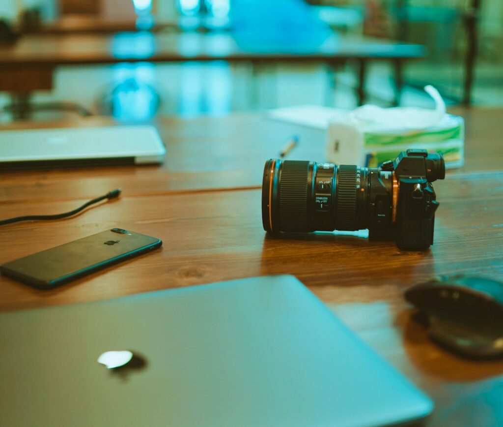 Camera, smartphone and closed laptops on a wooden table