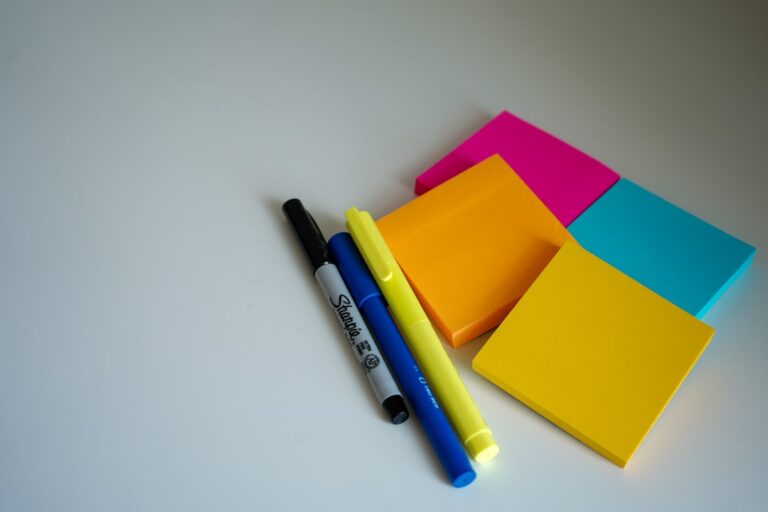 Colorful sticky notes and three markers on a white table