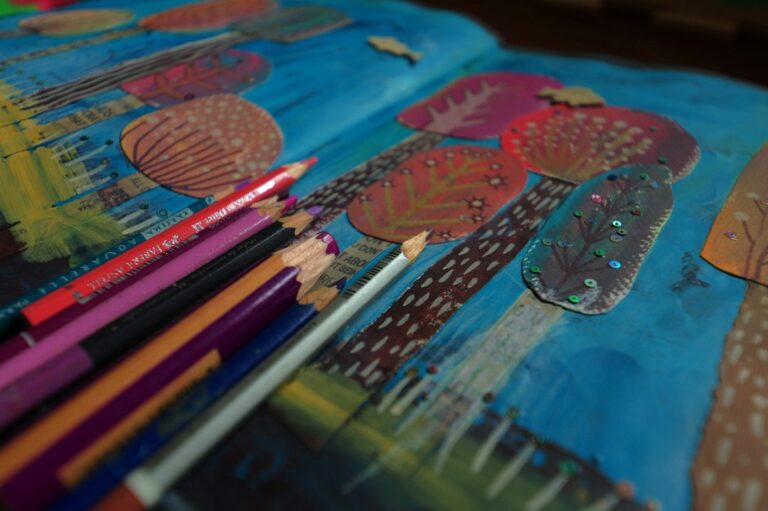 Colored pencils resting on a colorful handmade artwork