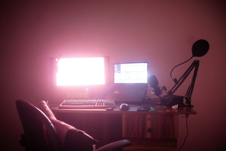 Desk with a laptop, monitor and microphone on an adjustable arm.