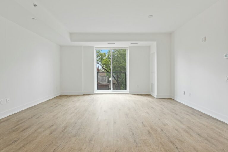Empty room with wood flooring, white walls, and a large window