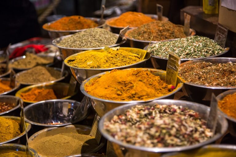 Bowls filled with colorful ground spices and dried herbs at a market