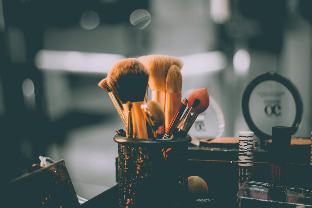 Makeup brushes in a holder beside cosmetic containers