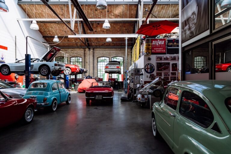 Classic cars parked inside a workshop with vehicle lifts and automotive signs.