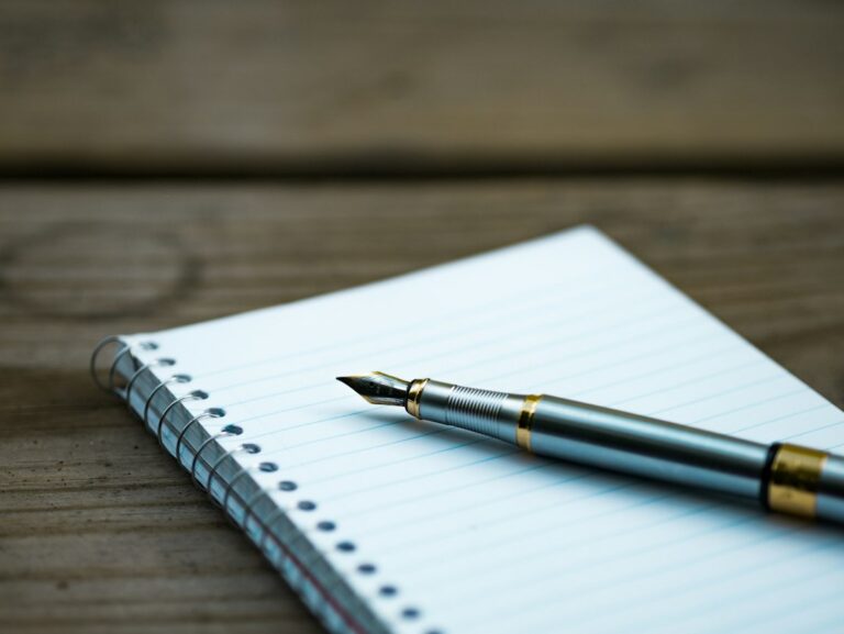 Fountain pen resting on an open lined notebook