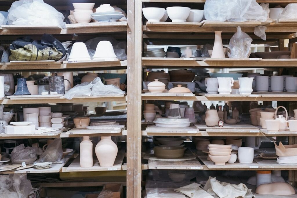 Ceramic cups, bowls, and vases arranged on wooden shelves.