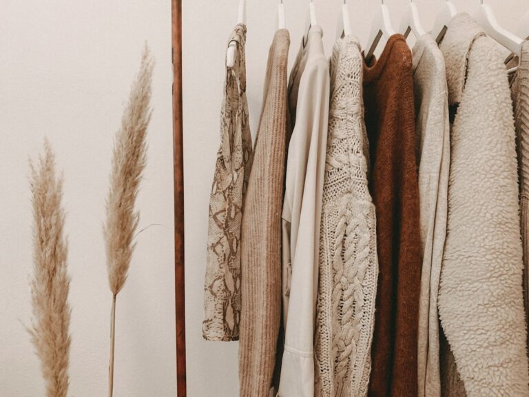 Neutral-colored garments and knitwear hanging beside dried grasses