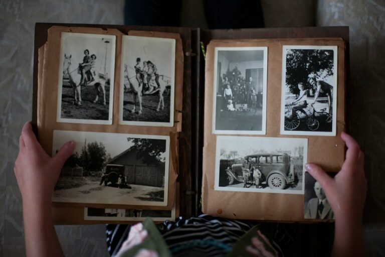 Hands holding an open album of old black-and-white family photographs.