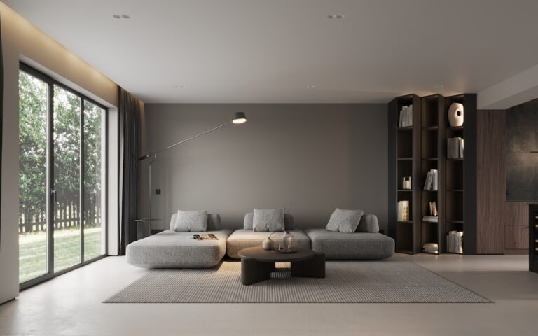 A gray sofa, low coffee table, and shelving in a living room beside large windows.