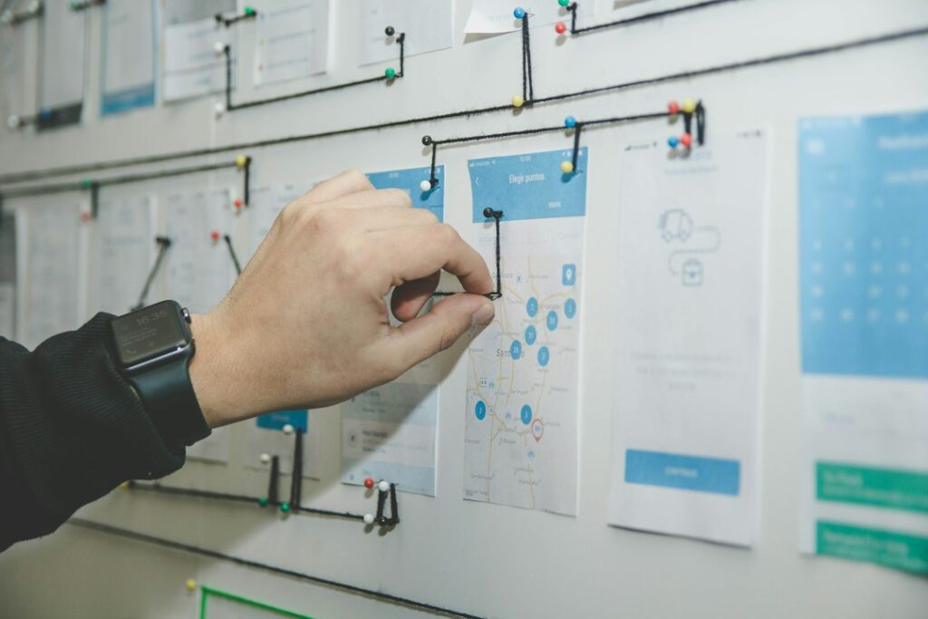 A hand adjusting a connection on a wall of project planning sketches.