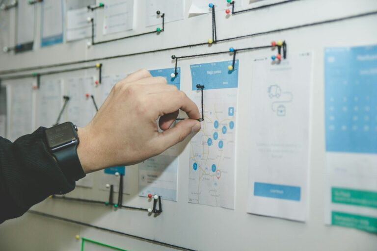 A hand adjusting a connection on a wall of project planning sketches.
