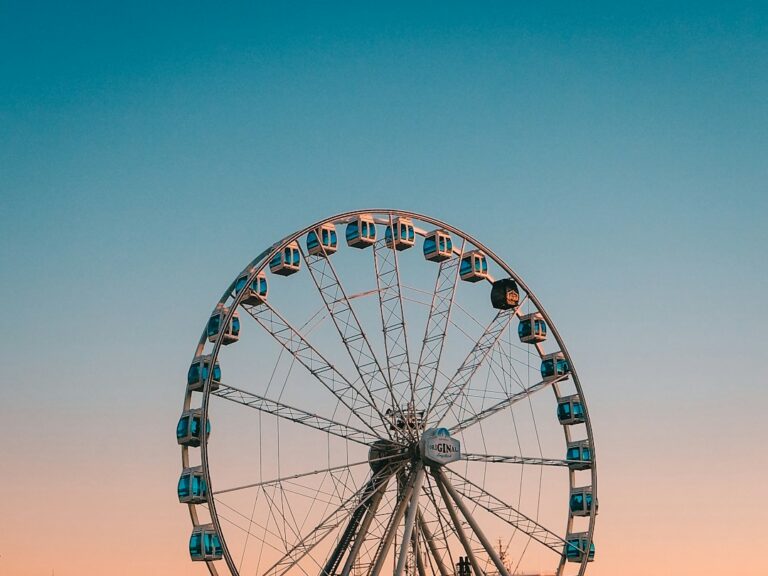 A large observation wheel with enclosed cabins beneath a clear blue sky.