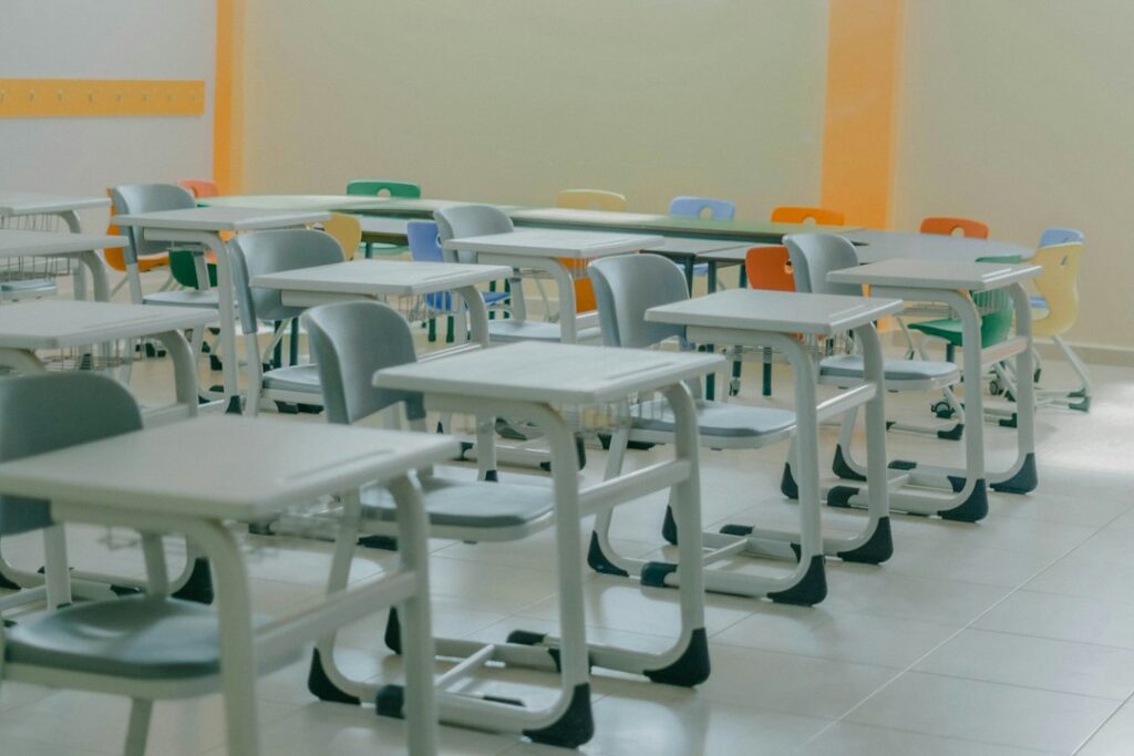 Rows of empty desks and chairs in a classroom.