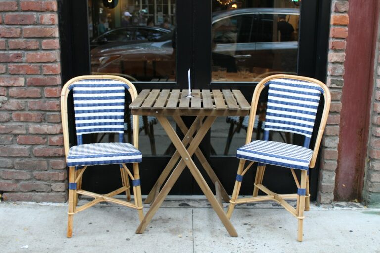 Two empty blue-and-white chairs facing a small outdoor café table.
