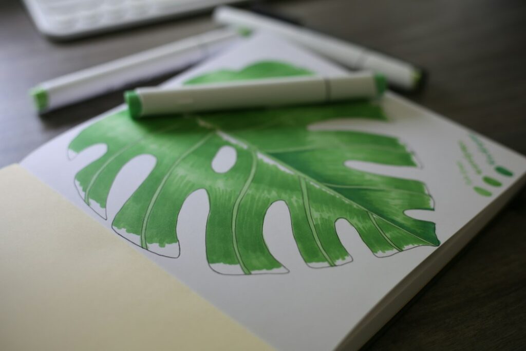 Green leaf drawing in a sketchbook with markers