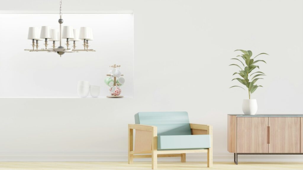 A bright interior with a pale blue chair, a wooden cabinet, a plant, and a hanging light.