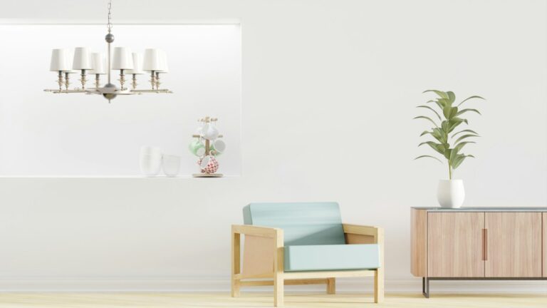 A bright interior with a pale blue chair, a wooden cabinet, a plant, and a hanging light.