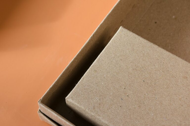 Close-up of a brown cardboard box and lid on an orange surface.