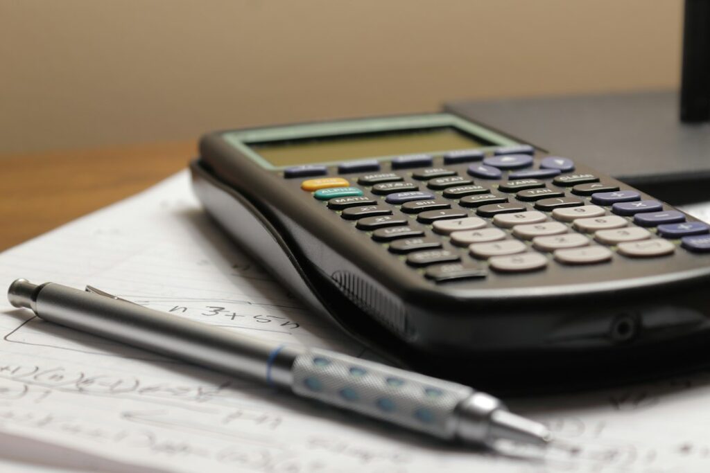 Calculator and pen resting on handwritten notes