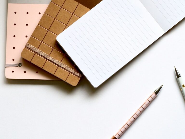 Three notebooks and two pencils arranged on a white surface.