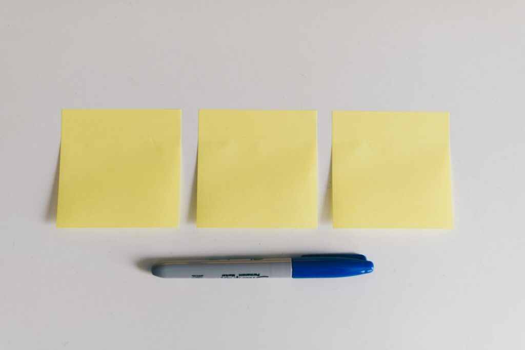 Three blank yellow sticky notes with a blue marker.