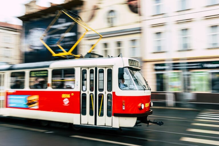 A red and white tram moving along a city street.