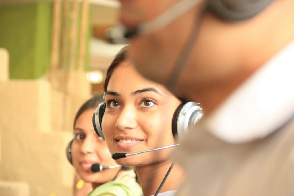 Customer service workers wearing telephone headsets in an office