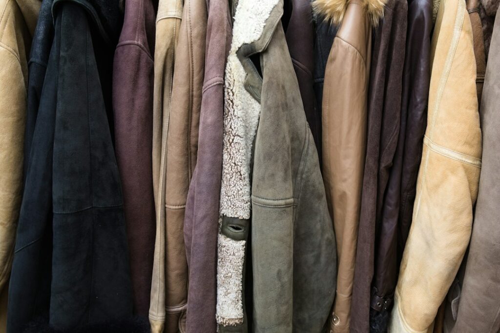 Brown, cream, and black jackets hanging together on a rail.