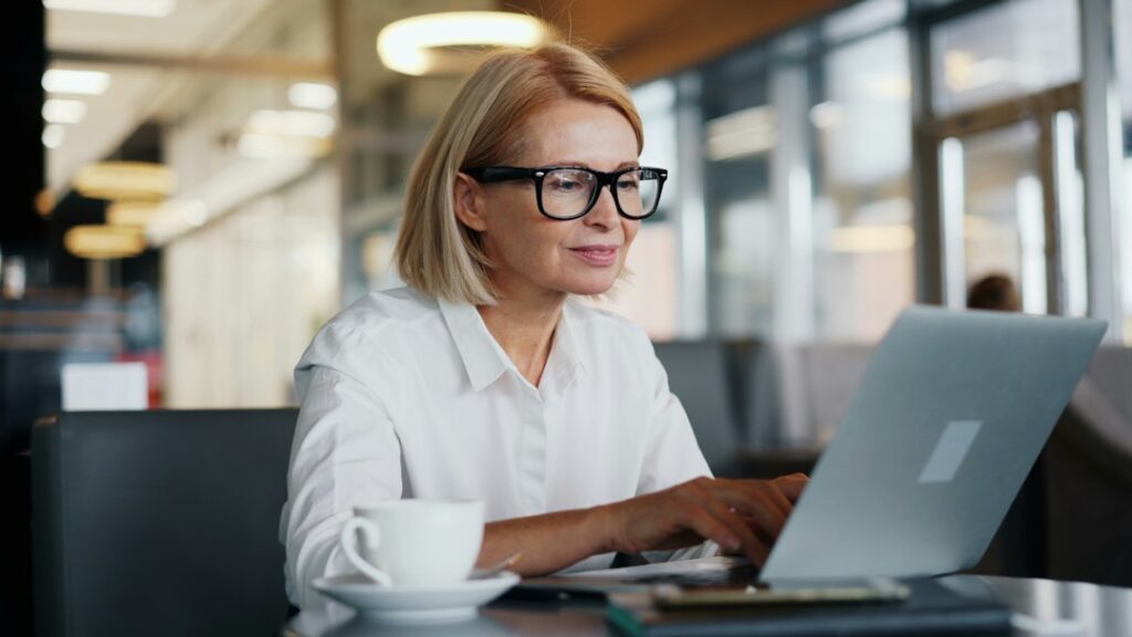 Woman with glasses working on a laptop at a table.