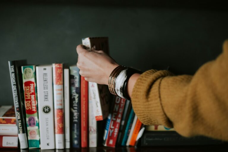A person reaching for a book on a shelf.