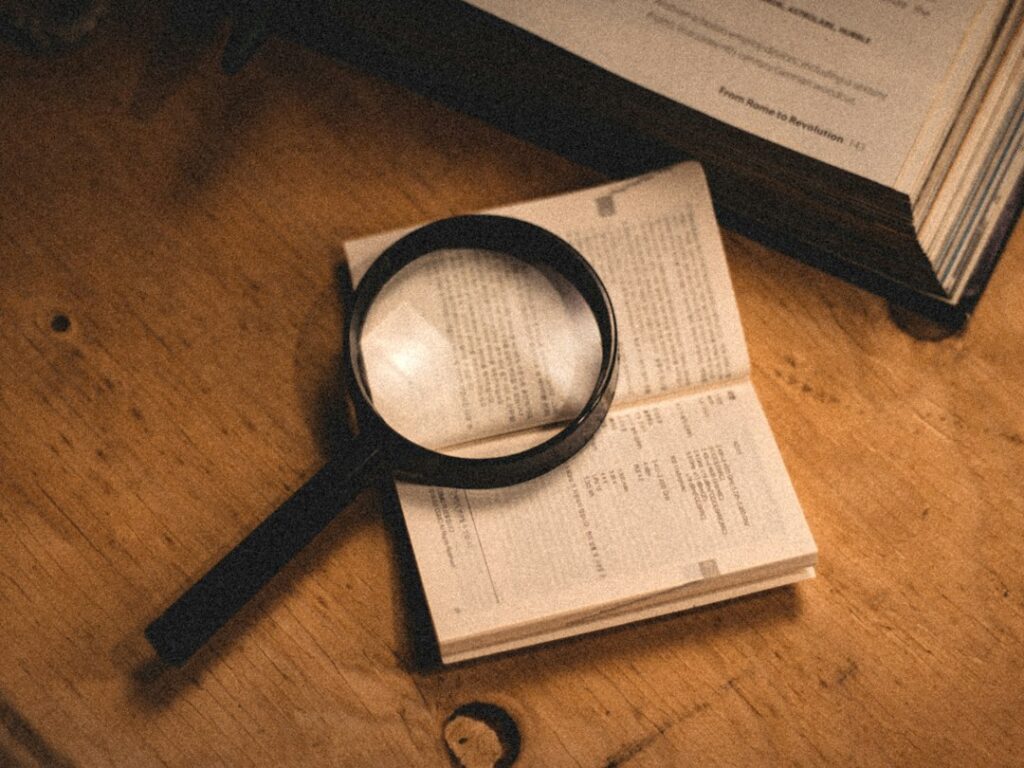 A magnifying glass resting on pages of an open book.