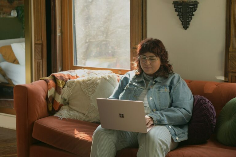 A woman using a laptop while sitting on a sofa at home