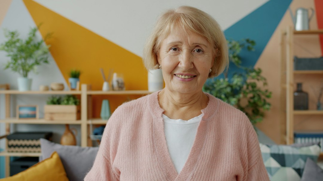 Mature woman smiling in a bright, calm home setting.