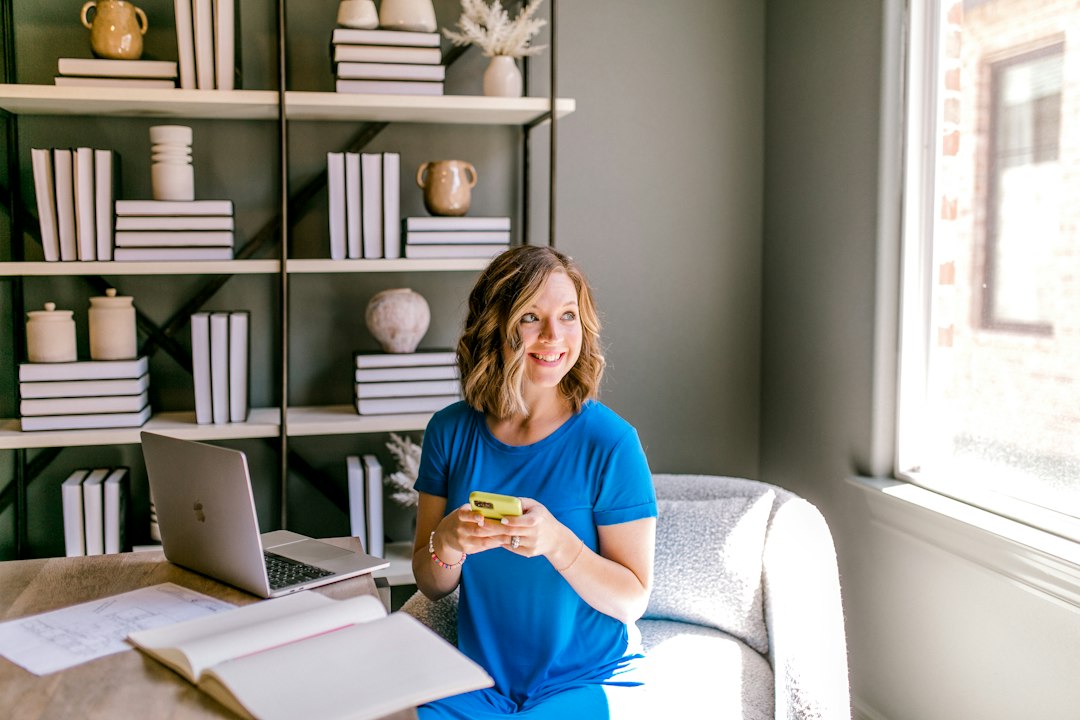 Woman using a laptop at a desk in a bright home workspace.