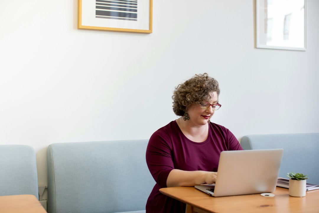 Woman working with a laptop in a bright office setting.